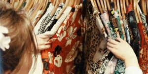 person holding assorted clothes in wooden hanger