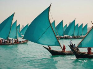 Traditional Emirati boats on turquoise waters with participants celebrating Al Dhafra Water Festival 2024 in vibrant attire.