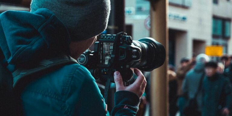 person in blue jacket holding black dslr camera