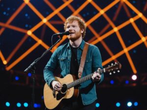 Ed Sheeran performing on stage in Dubai with mathematical symbols in the background during his Mathematics Concert Tour.