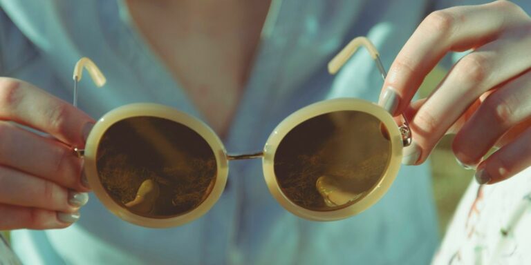 woman holding round sunglasses during daytime