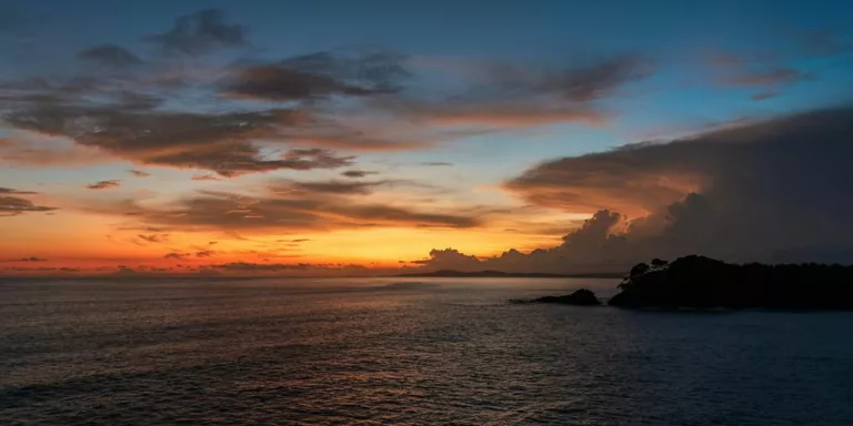 a sunset over a body of water with clouds in the sky