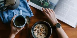 person holding blue ceramic mug and white magazine