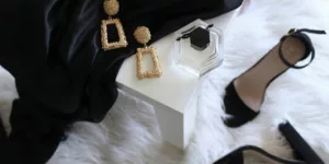 pair of gold-colored earrings on table and black ankle-strap pumps on area rug