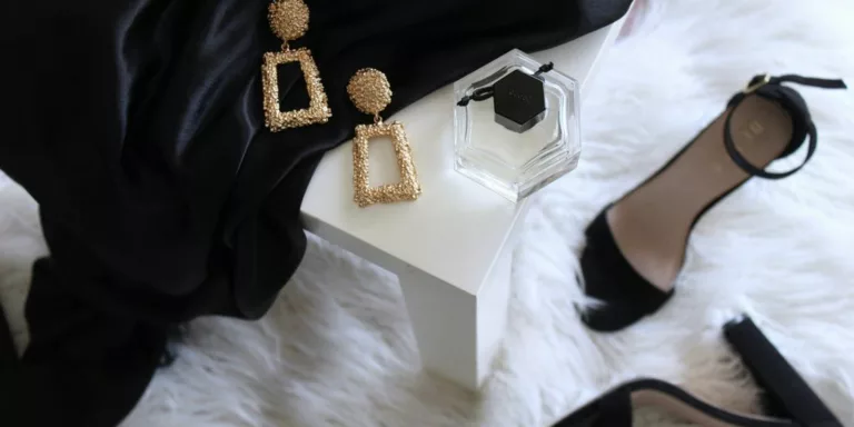 pair of gold-colored earrings on table and black ankle-strap pumps on area rug