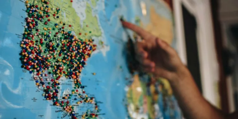 a person pointing at a map with pins on it