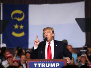 Trump speaking at podium with NC flag.