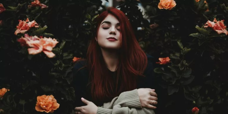 woman surrounded by green and yellow petaled flower hugging herself at daytime