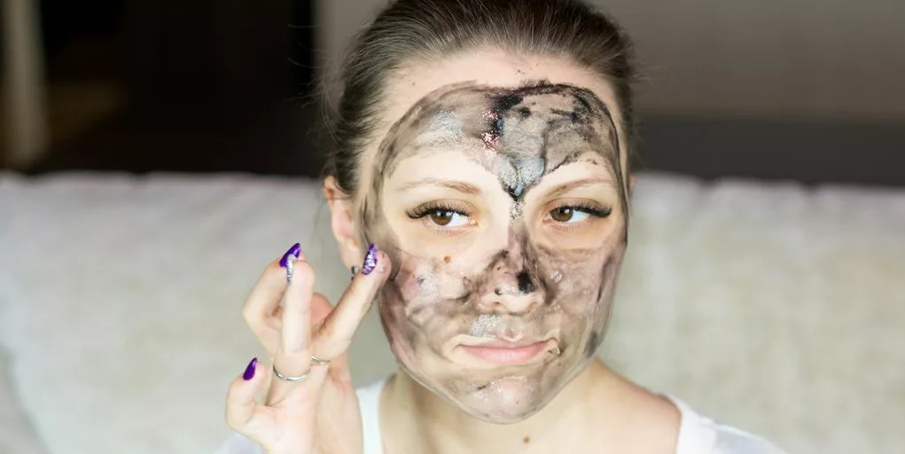 a woman with a face mask on holding her hand up to her face