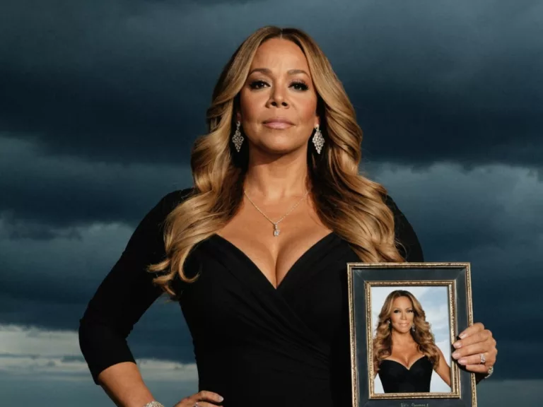 Mariah Carey holding a framed photo, looking somber