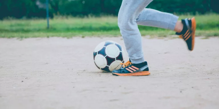 person plays soccer ball on white sands