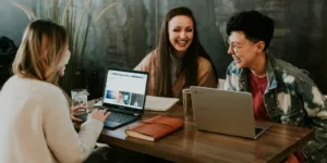 three people sitting in front of table laughing together