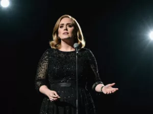 Adele on stage with a somber expression.