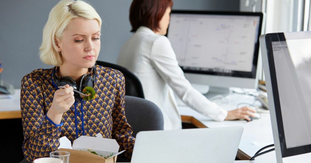 1_Female-designer-looking-at-laptop-during-working-lunch-at-office-desk