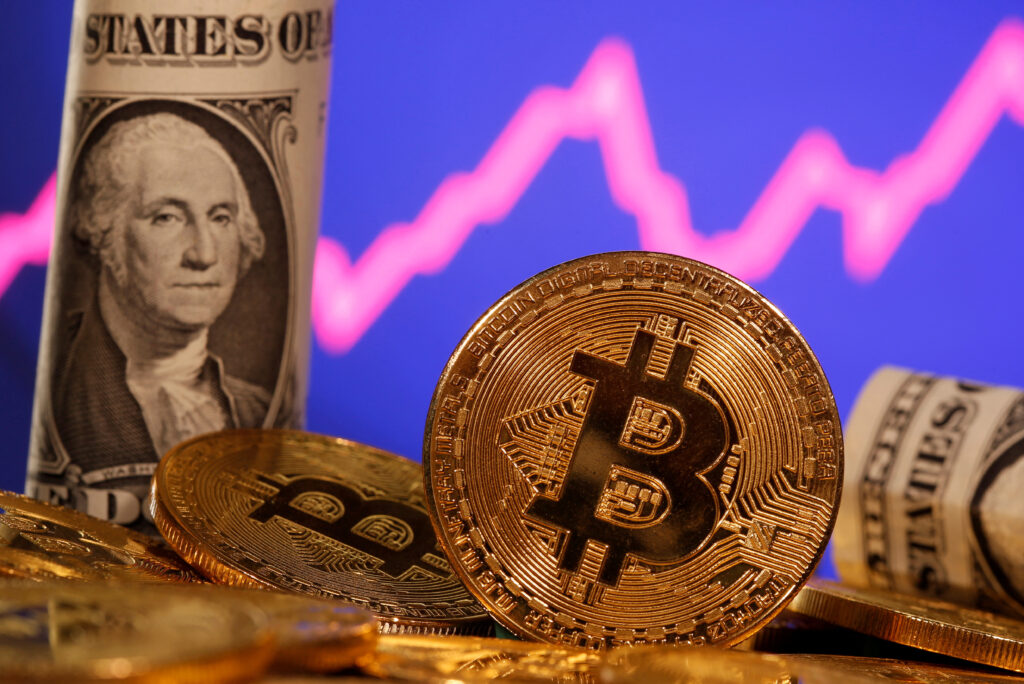 FILE PHOTO: A representation of virtual currency bitcoin and a U.S. one dollar banknote are seen in front of a stock graph in this illustration