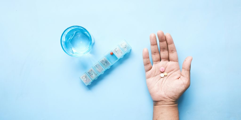 person holding pink and white medicine pill