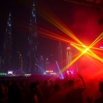Neon-lit Dubai skyline, vibrant club scene.