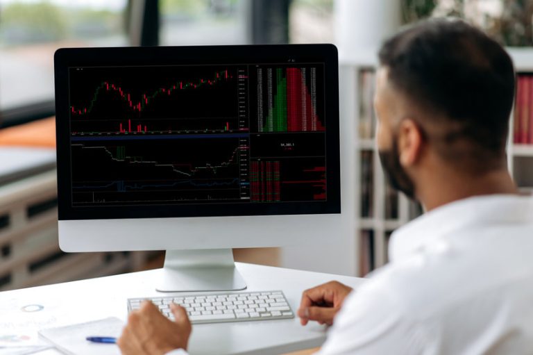 Successful smart concentrated confident Indian broke, trade analyst, sitting at computer in modern office, buying and selling cryptocurrencies, analyzing cryptocurrency market, looking at screen